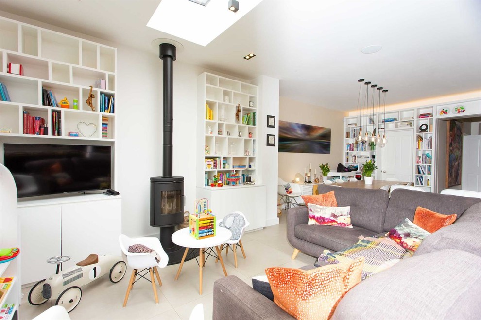 Diseño de salón abierto actual pequeño con paredes blancas, televisor colgado en la pared, estufa de leña y suelo beige