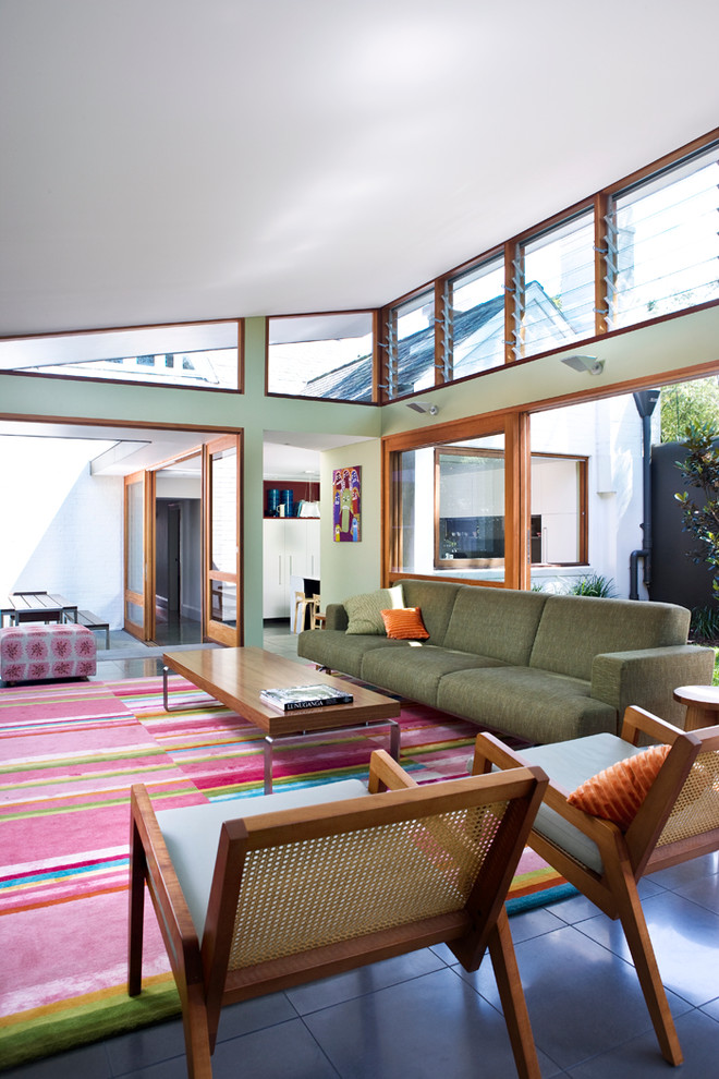 Example of a mid-sized minimalist open concept slate floor and black floor living room design in Sydney with green walls, no fireplace and a wall-mounted tv