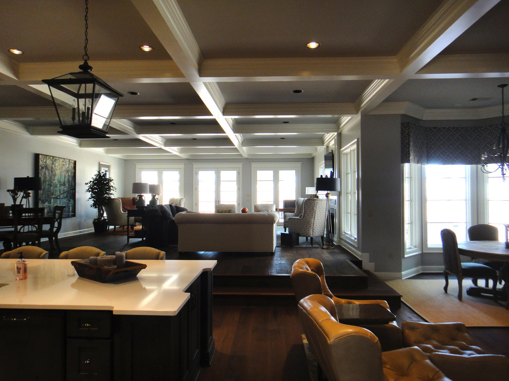 На фото: огромная открытая гостиная комната в классическом стиле с серыми стенами, темным паркетным полом, стандартным камином, фасадом камина из дерева и телевизором на стене с
