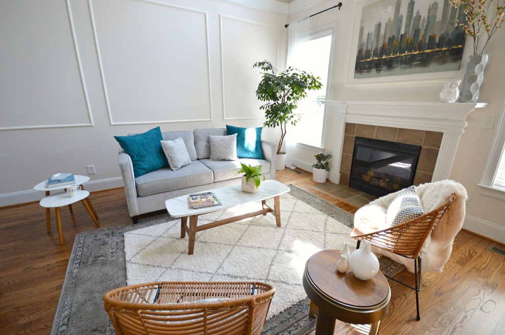 Foto di un grande soggiorno moderno aperto con pareti beige, pavimento in legno massello medio, camino classico, cornice del camino piastrellata e nessuna TV