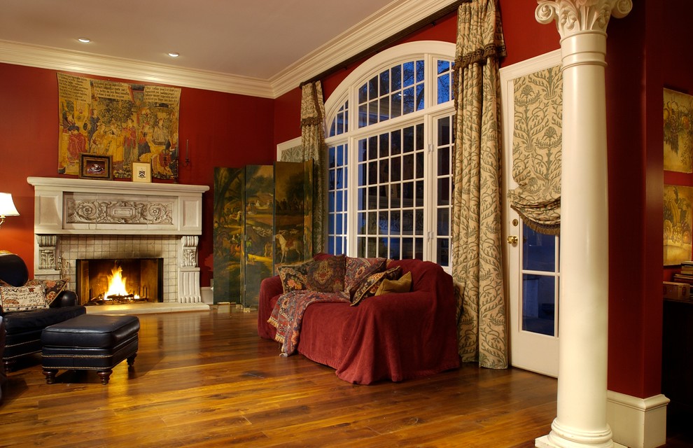 Cette photo montre un grand salon chic fermé avec une salle de réception, un mur rouge, un sol en bois brun, une cheminée standard, un manteau de cheminée en plâtre et aucun téléviseur.