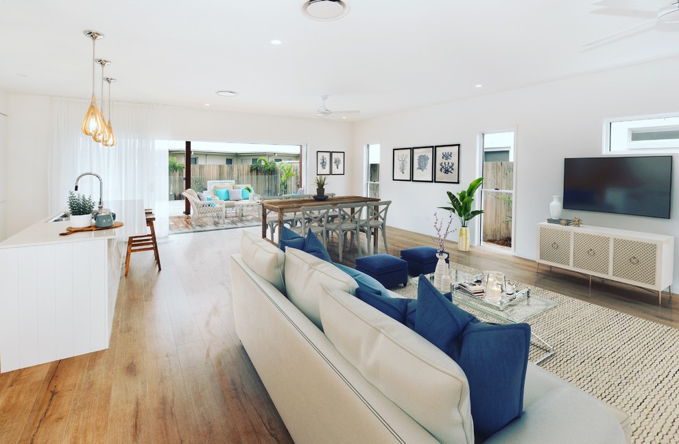 Example of a large beach style open concept laminate floor and brown floor living room design in Sunshine Coast with white walls and a wall-mounted tv