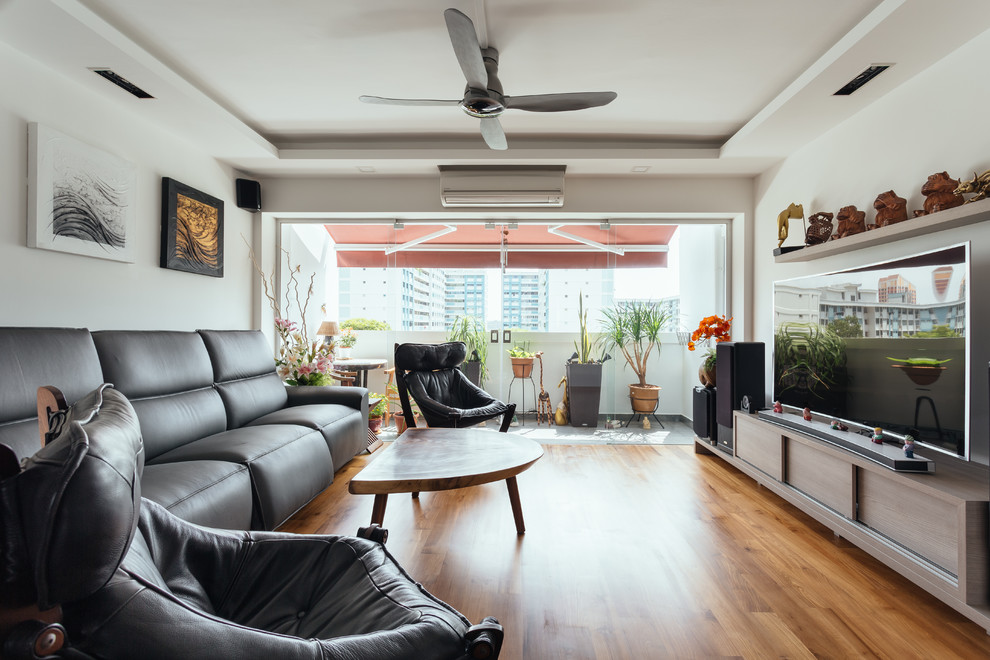 Abgetrenntes Asiatisches Wohnzimmer mit weißer Wandfarbe, braunem Holzboden, freistehendem TV und braunem Boden in Singapur