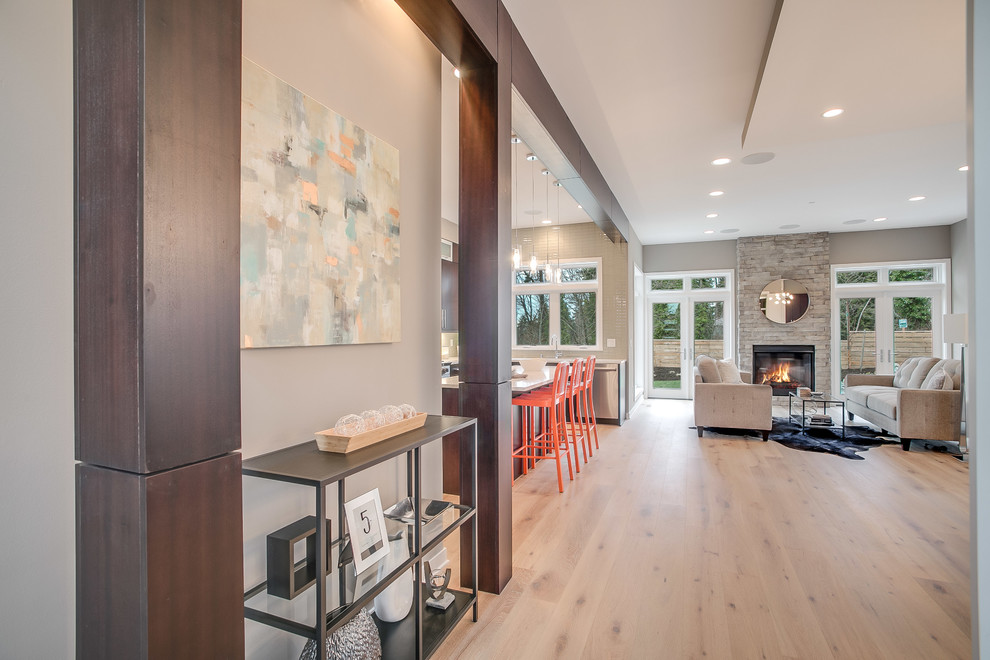 Mittelgroßes Modernes Wohnzimmer im Loft-Stil mit Hausbar, beiger Wandfarbe, hellem Holzboden, Kamin, Kaminumrandung aus Stein und beigem Boden in Seattle