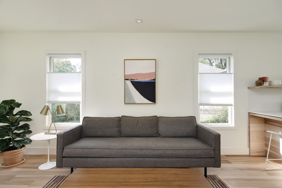 Kleines, Offenes Skandinavisches Wohnzimmer mit weißer Wandfarbe, hellem Holzboden, TV-Wand und braunem Boden in Austin