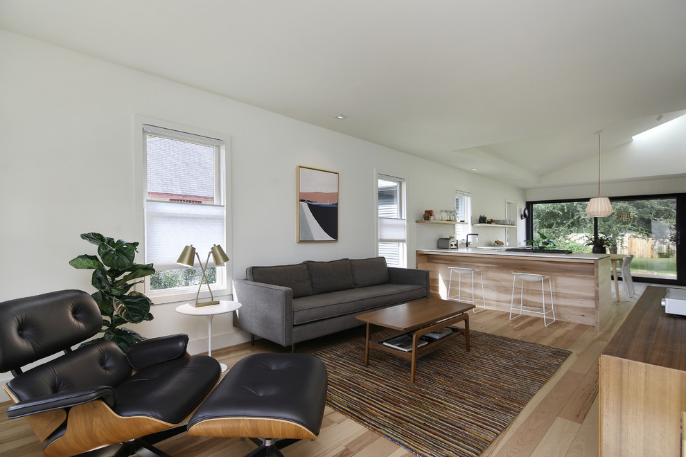 Kleines, Offenes Nordisches Wohnzimmer mit weißer Wandfarbe, hellem Holzboden, TV-Wand und braunem Boden in Austin