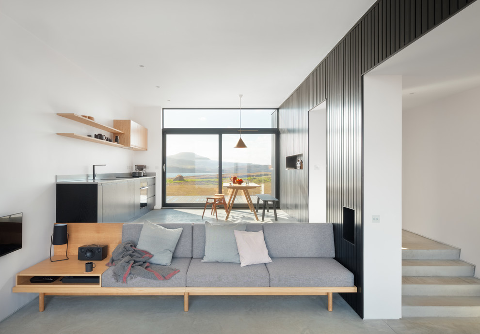 Modern open plan living room in Other with black walls, a wall mounted tv and grey floors.