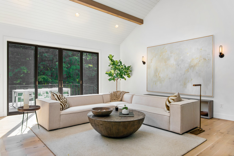Imagen de salón abierto actual grande con paredes blancas, suelo de madera clara y suelo beige