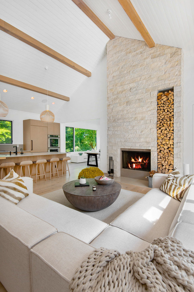 Ejemplo de salón abierto minimalista grande con paredes blancas, suelo de madera clara, todas las chimeneas, marco de chimenea de piedra y suelo beige
