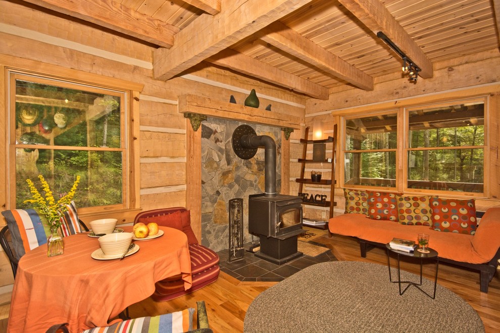 Ispirazione per un piccolo soggiorno rustico aperto con pareti beige, pavimento in legno massello medio, stufa a legna e nessuna TV