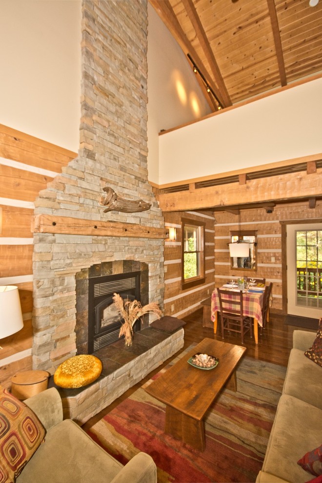 Mid-sized mountain style open concept dark wood floor living room photo in Other with beige walls, a standard fireplace, a stone fireplace and no tv
