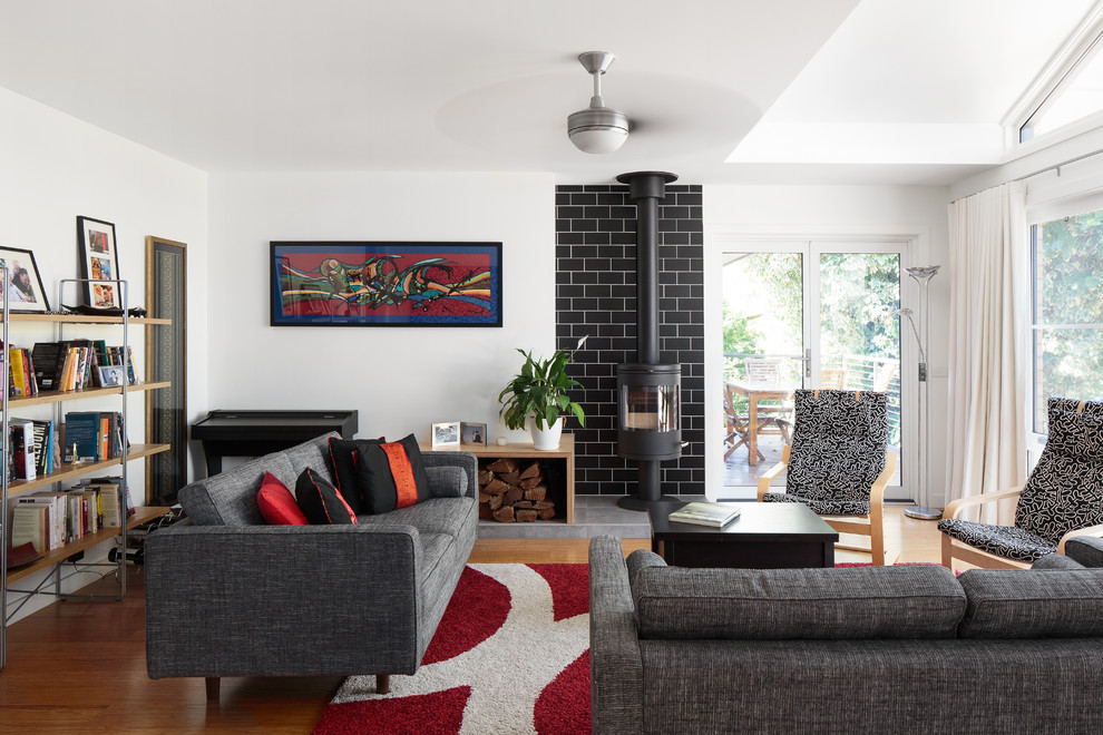 Photo of a bohemian formal enclosed living room in Canberra - Queanbeyan with white walls, medium hardwood flooring, a wood burning stove, a metal fireplace surround, no tv and brown floors.