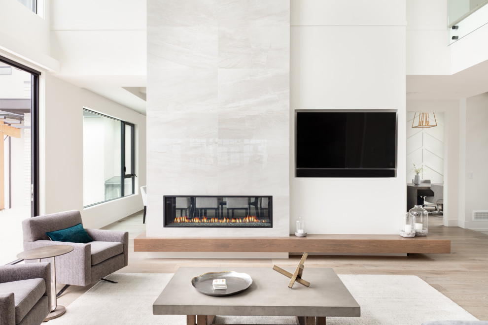 Offenes Modernes Wohnzimmer mit weißer Wandfarbe, hellem Holzboden, Tunnelkamin, TV-Wand und beigem Boden in Vancouver