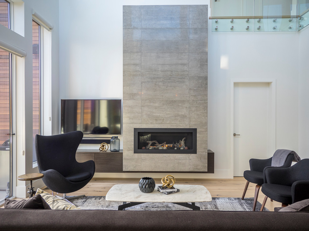 This is an example of a medium sized contemporary mezzanine living room in Vancouver with white walls, light hardwood flooring, a hanging fireplace, a tiled fireplace surround and a wall mounted tv.