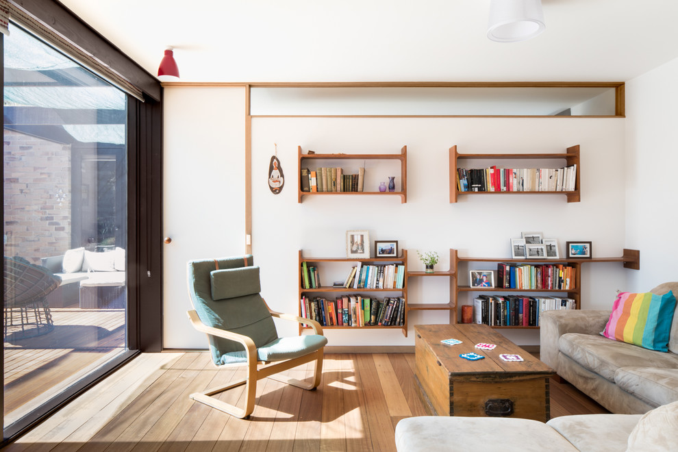 This is an example of a medium sized retro open plan living room in Melbourne with white walls, light hardwood flooring, no fireplace, no tv and brown floors.