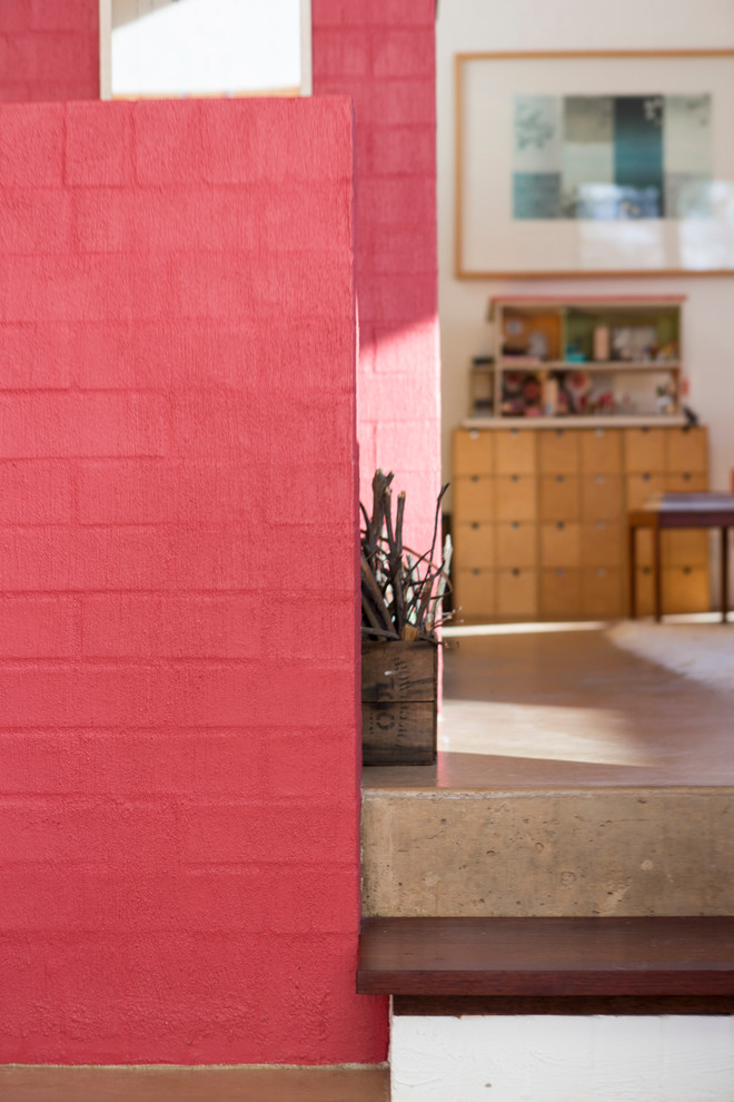 Esempio di un piccolo soggiorno contemporaneo aperto con pareti rosa, pavimento in cemento, stufa a legna e cornice del camino in mattoni