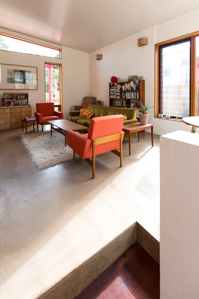 Immagine di un piccolo soggiorno design aperto con pareti bianche e pavimento in cemento