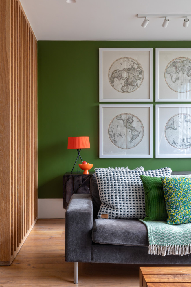 Cette image montre un grand salon design ouvert avec un mur vert, parquet clair et un téléviseur fixé au mur.