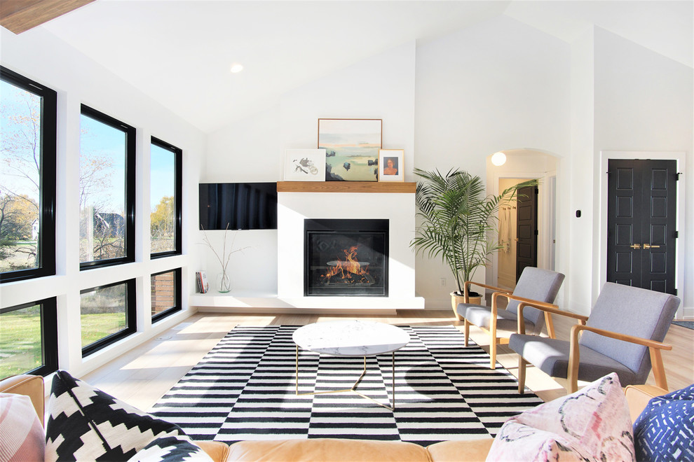 Photo of a large scandinavian formal open plan living room in Grand Rapids with white walls, light hardwood flooring, a standard fireplace, a plastered fireplace surround, a wall mounted tv and beige floors.