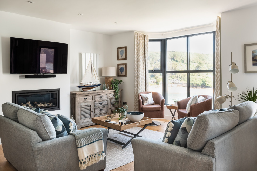 Photo of a large traditional open plan living room in Devon with white walls, a metal fireplace surround, a wall mounted tv, medium hardwood flooring, a ribbon fireplace and beige floors.