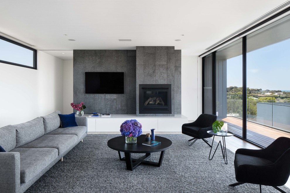 Modernes Wohnzimmer mit weißer Wandfarbe, hellem Holzboden, Kamin, gefliester Kaminumrandung, TV-Wand und beigem Boden in Melbourne