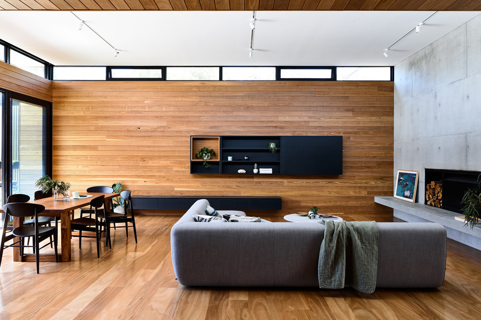 Idées déco pour un salon contemporain ouvert avec un mur marron, un sol en bois brun, une cheminée standard, un manteau de cheminée en béton, un téléviseur dissimulé et un sol marron.