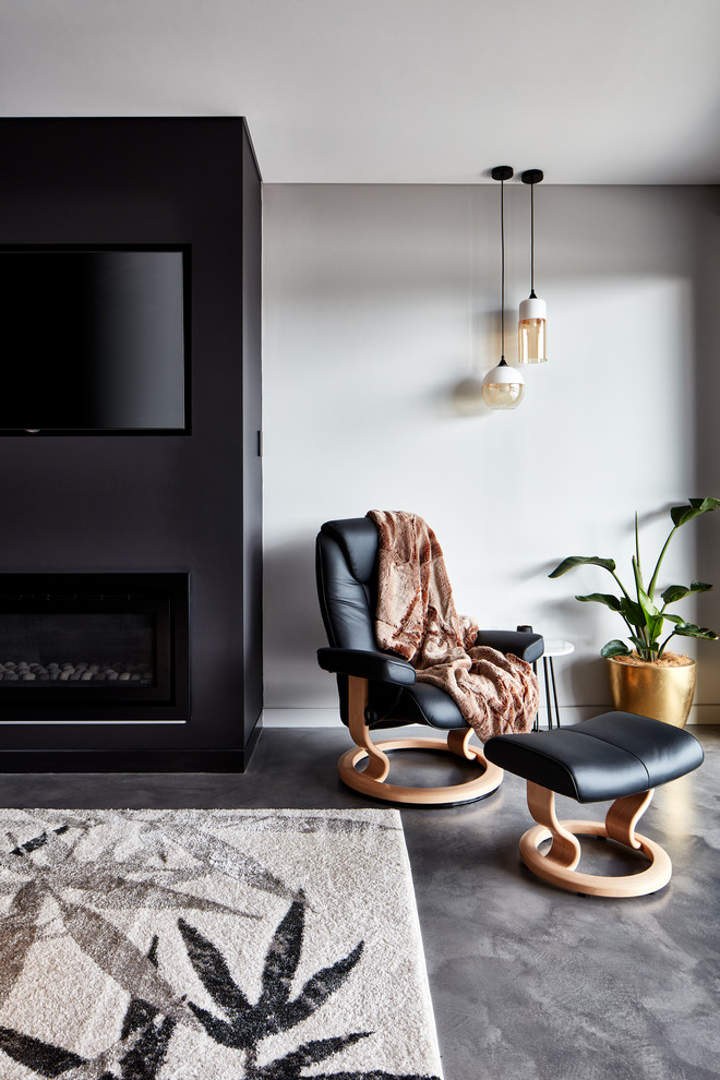 На фото: гостиная комната в стиле модернизм с серыми стенами, стандартным камином и телевизором на стене