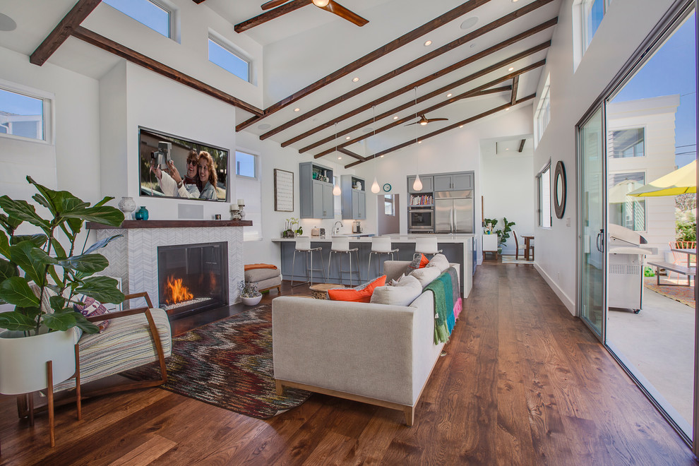 Offenes, Großes Modernes Wohnzimmer mit weißer Wandfarbe, Kamin, TV-Wand, braunem Holzboden und Kaminumrandung aus Stein in Los Angeles