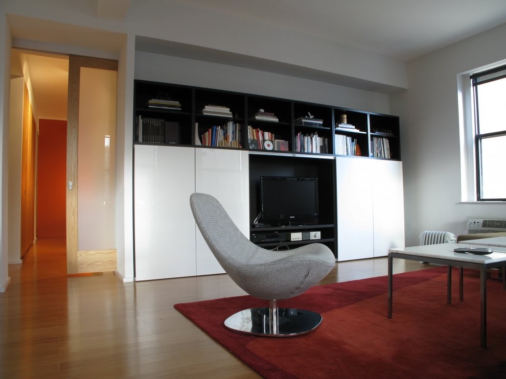 Diseño de salón abierto moderno con paredes blancas, suelo de madera clara y pared multimedia