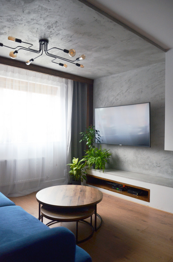 Пример оригинального дизайна: маленькая парадная, изолированная гостиная комната в стиле фьюжн с синими стенами, полом из ламината, двусторонним камином, фасадом камина из штукатурки, телевизором на стене, коричневым полом и многоуровневым потолком для на участке и в саду