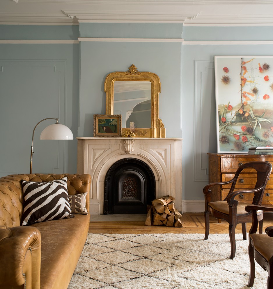 Cette photo montre un salon chic avec un mur bleu, un sol en bois brun, une cheminée standard et un sol marron.