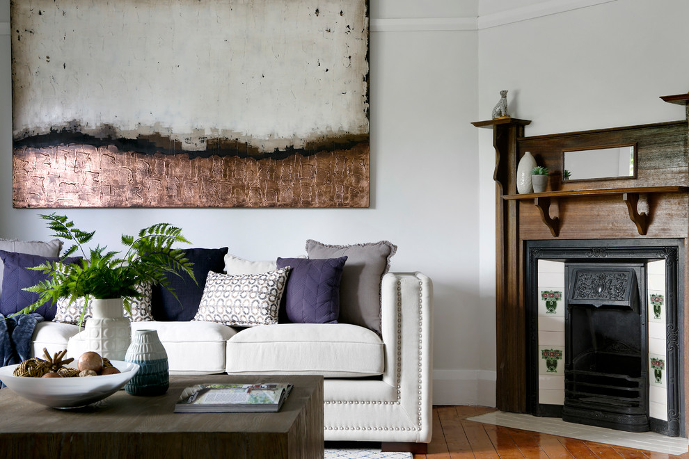 Repräsentatives, Fernseherloses, Abgetrenntes Klassisches Wohnzimmer mit weißer Wandfarbe, braunem Holzboden, Eckkamin, Kaminumrandung aus Holz und braunem Boden in Sydney