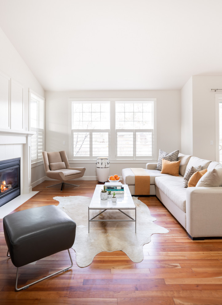 Photo of a medium sized contemporary living room in Other with white walls, medium hardwood flooring, a standard fireplace, a wooden fireplace surround and a concealed tv.