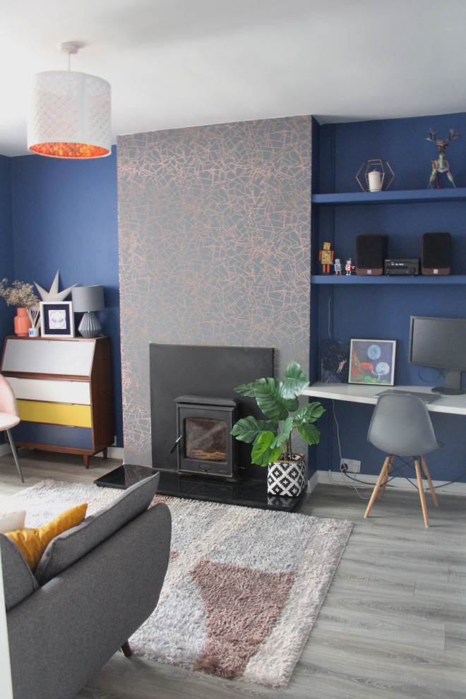Foto de salón abierto bohemio de tamaño medio sin televisor con paredes azules, suelo laminado, estufa de leña, marco de chimenea de metal y suelo marrón