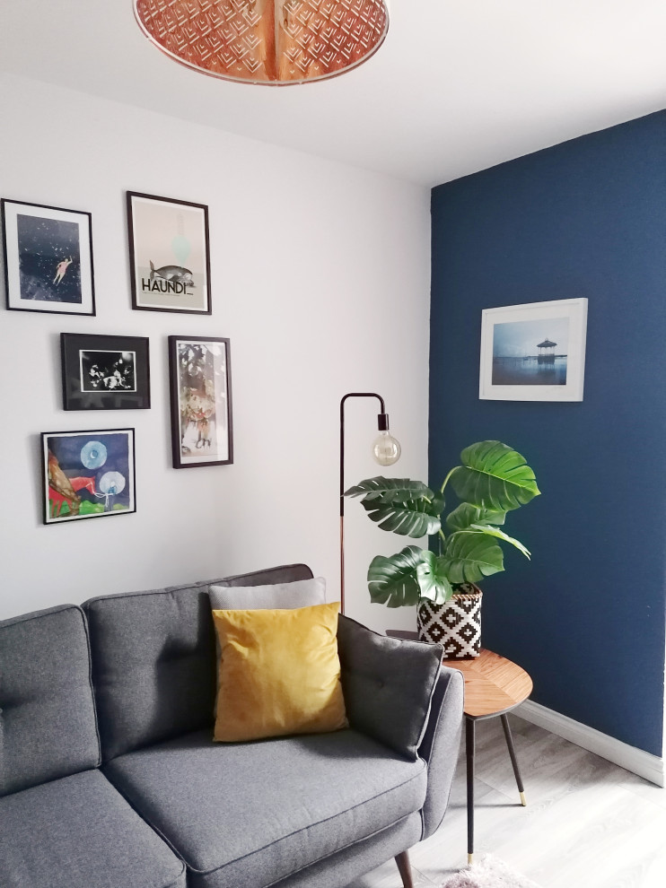 На фото: открытая гостиная комната среднего размера в стиле фьюжн с синими стенами, полом из ламината, печью-буржуйкой, фасадом камина из металла и коричневым полом без телевизора