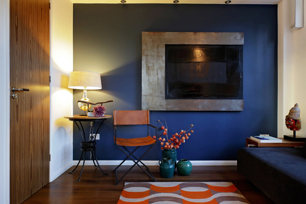 Example of a mid-sized trendy enclosed medium tone wood floor living room design in London with a bar, blue walls, no fireplace and no tv