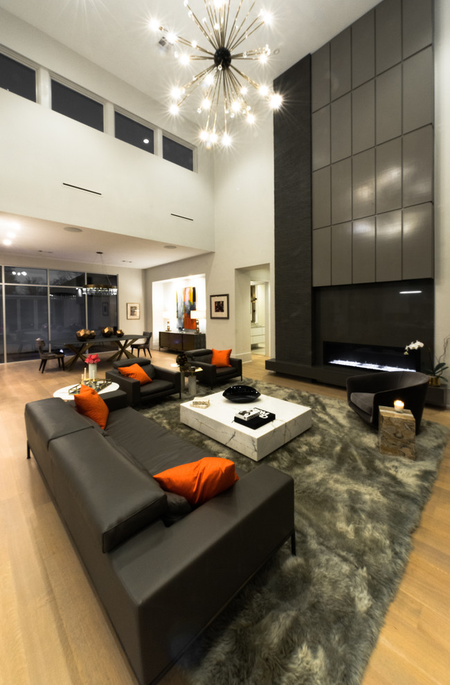 Modelo de salón abierto minimalista grande sin televisor con paredes blancas, suelo de madera en tonos medios y todas las chimeneas