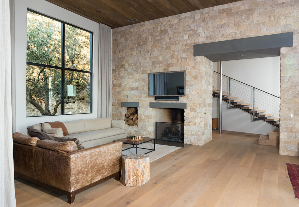 Photo of an expansive contemporary formal open plan living room in Los Angeles with white walls, light hardwood flooring, a standard fireplace, a stone fireplace surround, a wall mounted tv and brown floors.
