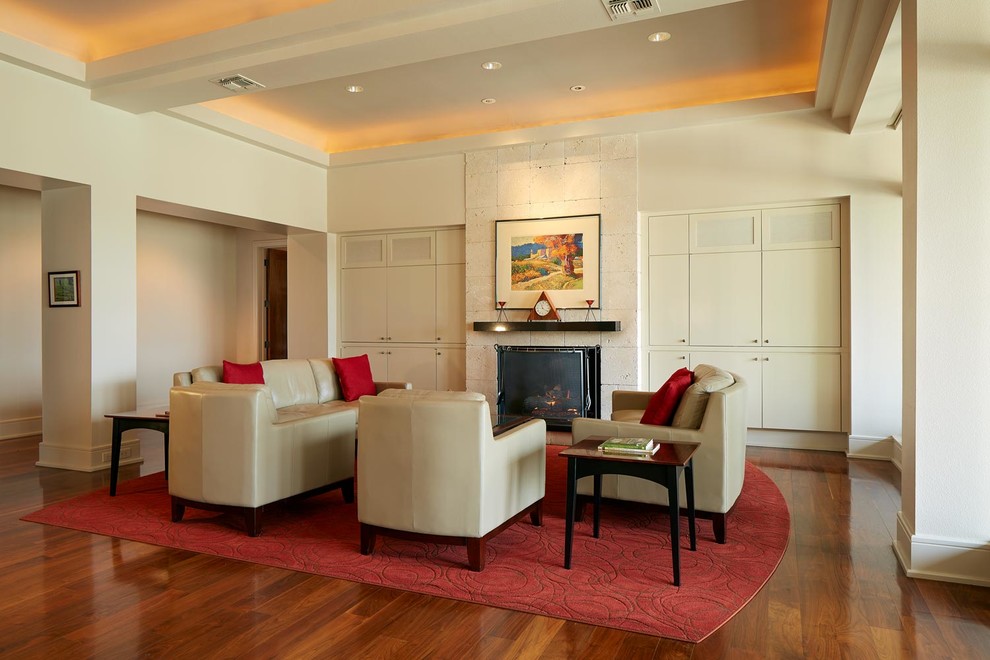 Exemple d'un grand salon tendance ouvert avec une salle de réception, un mur blanc, un sol en bois brun, une cheminée standard, un manteau de cheminée en pierre et aucun téléviseur.