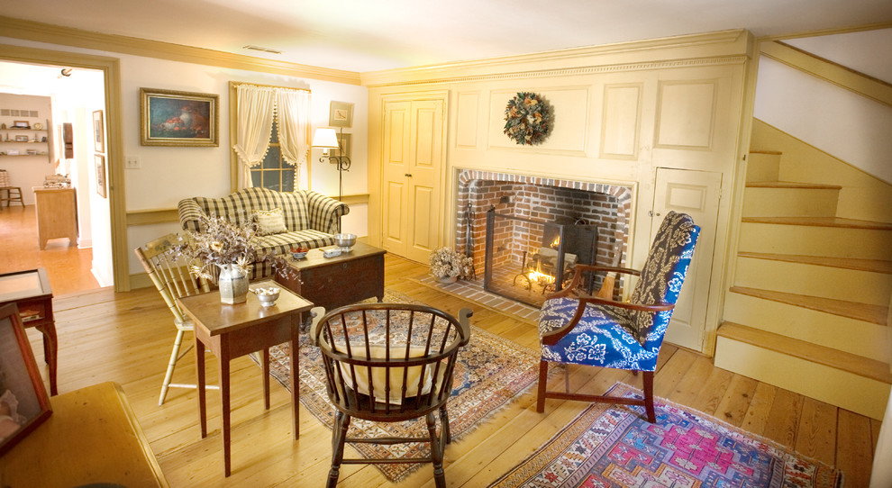 Foto de salón para visitas cerrado clásico pequeño con paredes amarillas, suelo de madera en tonos medios, todas las chimeneas y marco de chimenea de ladrillo