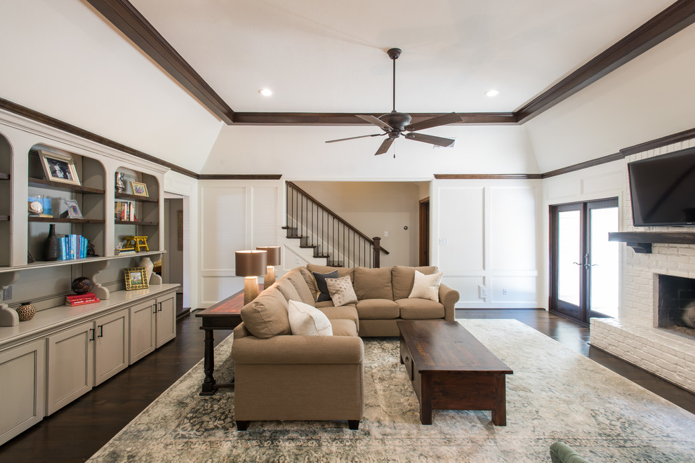 This is an example of a medium sized classic enclosed living room in Houston with white walls, dark hardwood flooring, a standard fireplace, a brick fireplace surround, a wall mounted tv and feature lighting.