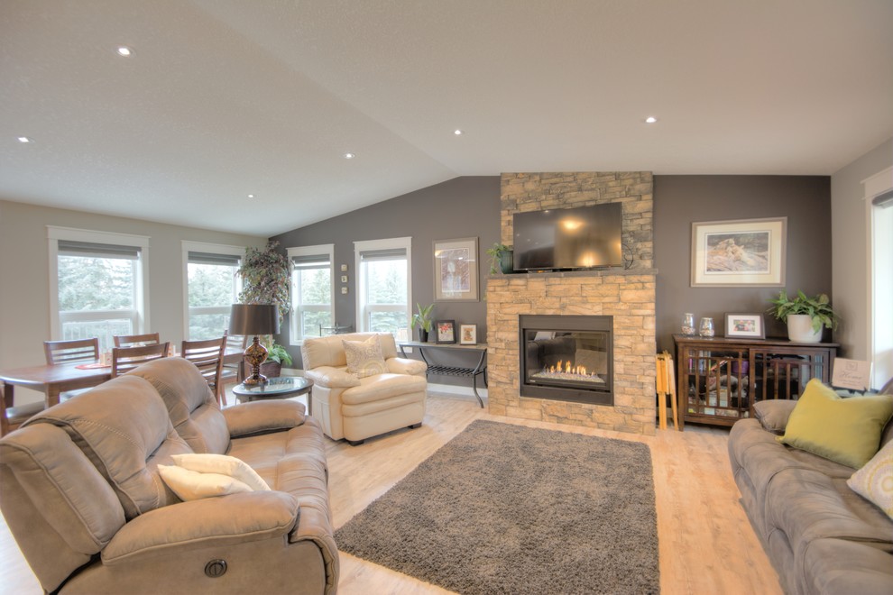 Photo of a medium sized modern open plan living room with multi-coloured walls, laminate floors, a standard fireplace, a stone fireplace surround and no tv.