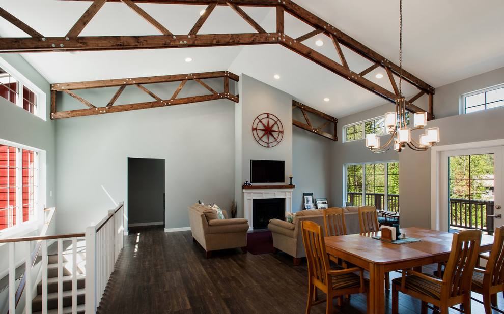 This is an example of an expansive rural open plan living room in Seattle with grey walls, dark hardwood flooring, a standard fireplace, a wooden fireplace surround and a wall mounted tv.
