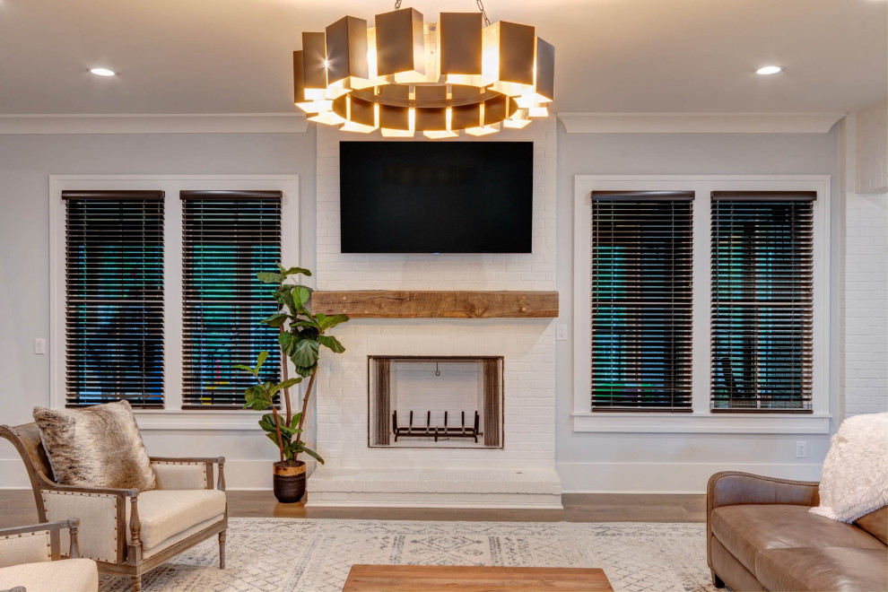 Inspiration for an expansive modern open plan living room in Atlanta with a home bar, grey walls, medium hardwood flooring, a standard fireplace, a brick fireplace surround, a wall mounted tv, brown floors and brick walls.