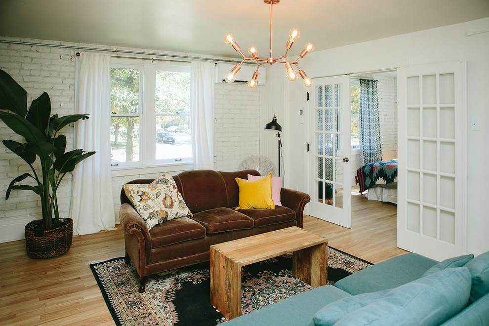 This is an example of a medium sized bohemian living room in Denver with white walls and light hardwood flooring.