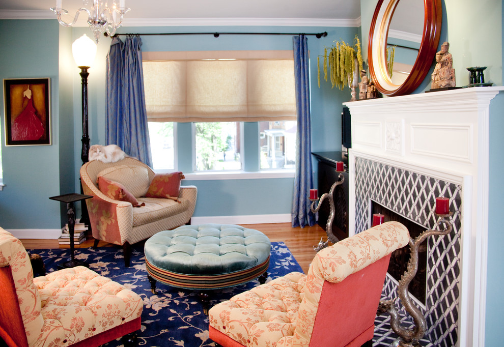 На фото: гостиная комната в стиле фьюжн с синими стенами, фасадом камина из плитки и красивыми шторами с
