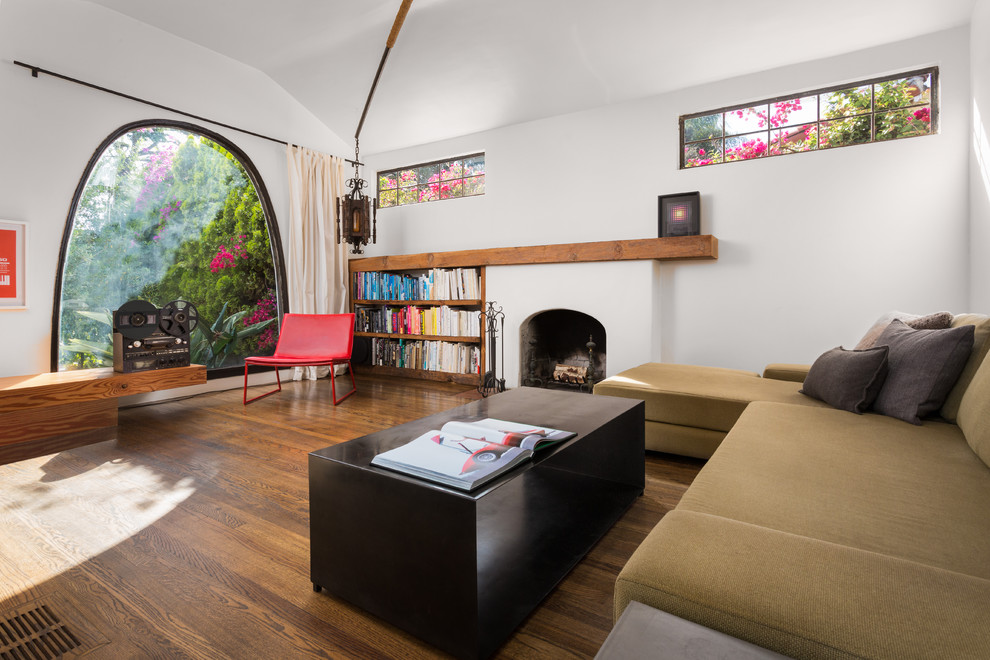 Kleines, Fernseherloses, Offenes Modernes Wohnzimmer mit weißer Wandfarbe, Kamin, braunem Holzboden, verputzter Kaminumrandung und braunem Boden in Los Angeles