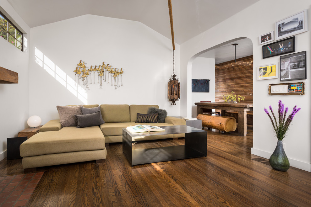 Modelo de salón abierto contemporáneo pequeño sin televisor con paredes blancas, suelo de madera en tonos medios, todas las chimeneas, marco de chimenea de yeso y suelo marrón