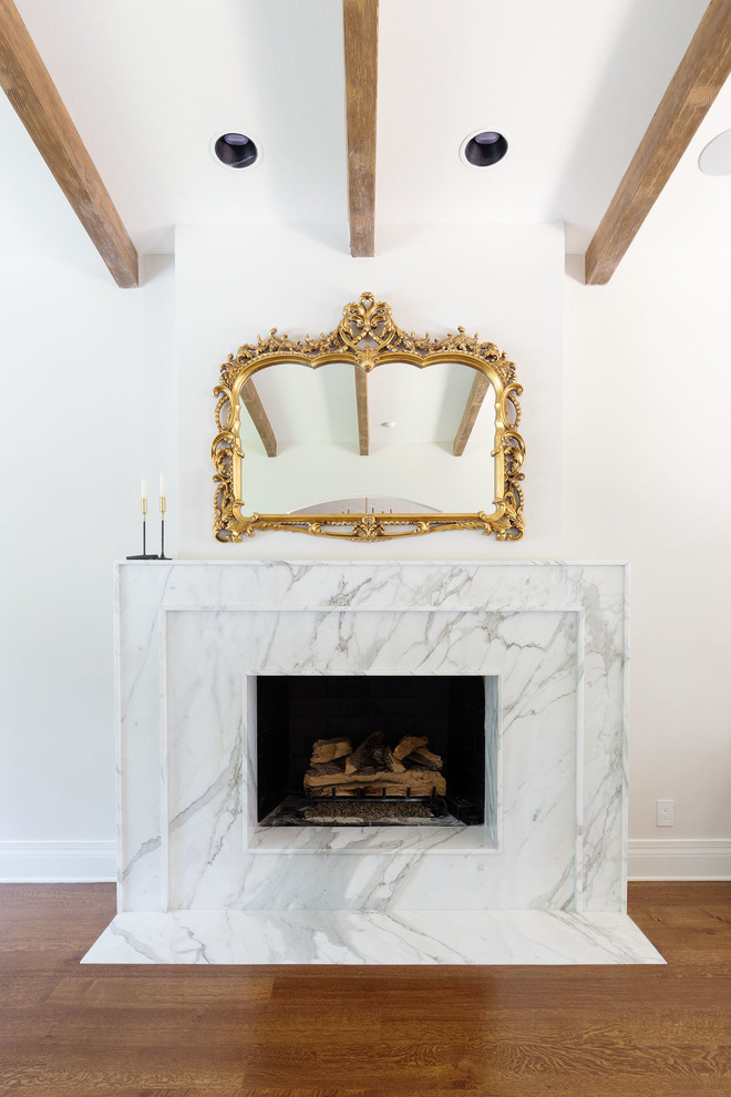 Offenes Mediterranes Wohnzimmer mit weißer Wandfarbe, braunem Holzboden, Gaskamin und gefliester Kaminumrandung in Orange County