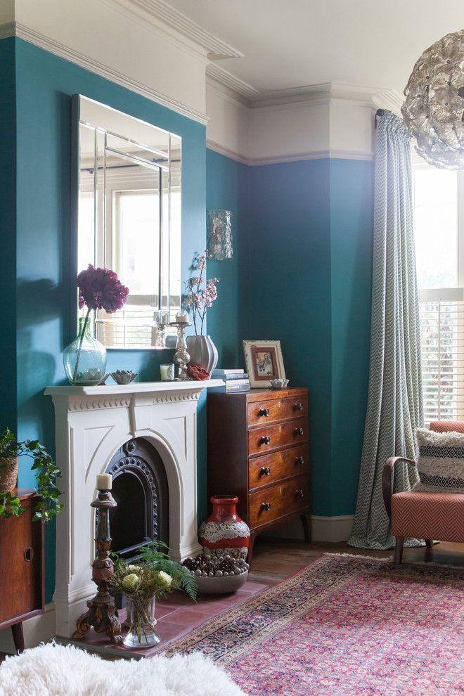 Kleines, Offenes Stilmix Wohnzimmer mit blauer Wandfarbe, braunem Holzboden, Kamin, Kaminumrandung aus Metall und freistehendem TV in London
